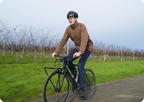 Homme à vélo sur route rurale avec vignes en arrière-plan